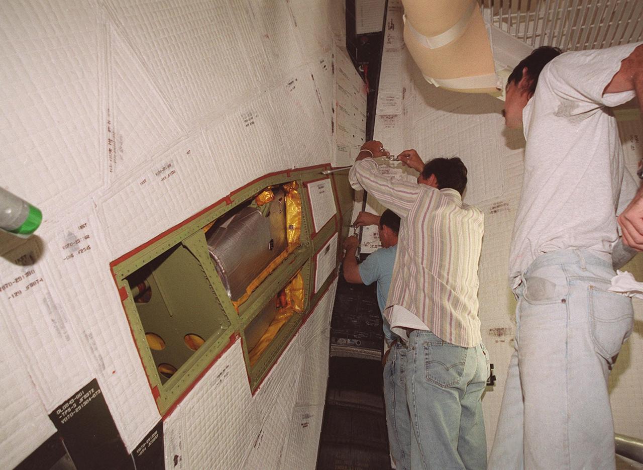 KENNEDY SPACE CENTER, FLA. -- Technicians at Launch Pad 39A begin removing thermal blankets and panels from a site near the tail of Space Shuttle Atlantis in order to reach the power drive unit (PDU) inside. The PDU controls the rudder/speed brake on the orbiter. From left to right are Mark Noel, Bob Wright and Tod Biddle, with United Space Alliance. Shuttle managers decided to replace the faulty PDU, about the size of an office copy machine, at the launch pad. If successful, launch preparations will continue as planned, with liftoff targeted for April 24 at 4:15 p.m. on mission STS-101. The mission is the third assembly flight for the International Space Station, carrying logistics and supplies to the Space Station, plus the crew will be preparing the Station for the arrival of the Zvezda Service Module, expected to be launched by Russia in July 2000. The crew will conduct one space walk to perform maintenance on the Space Station