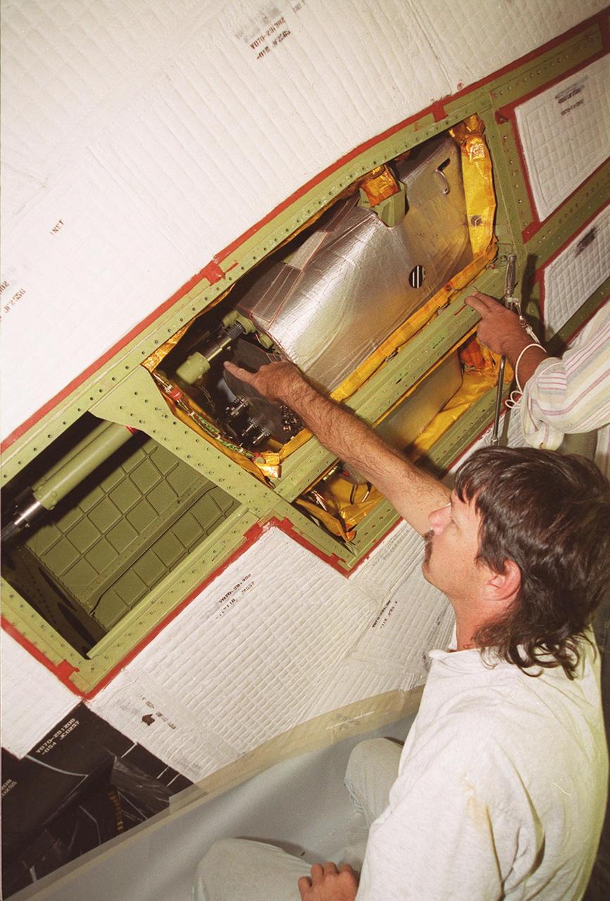 KENNEDY SPACE CENTER, FLA. -- With coverings removed from a site near the tail of Space Shuttle Atlantis, Tod Biddle, a United Space Alliance (USA) technician, points to the power drive unit (PDU) inside. The PDU controls the rudder/speed brake on the orbiter. The hands at right belong to Bob Wright, also a USA technician. Shuttle managers decided to replace the faulty PDU, about the size of an office copy machine, at the launch pad. If successful, launch preparations will continue as planned, with liftoff targeted for April 24 at 4:15 p.m. on mission STS-101. The mission is the third assembly flight for the International Space Station, carrying logistics and supplies to the Space Station, plus the crew will be preparing the Station for the arrival of the Zvezda Service Module, expected to be launched by Russia in July 2000. The crew will conduct one space walk to perform maintenance on the Space Station