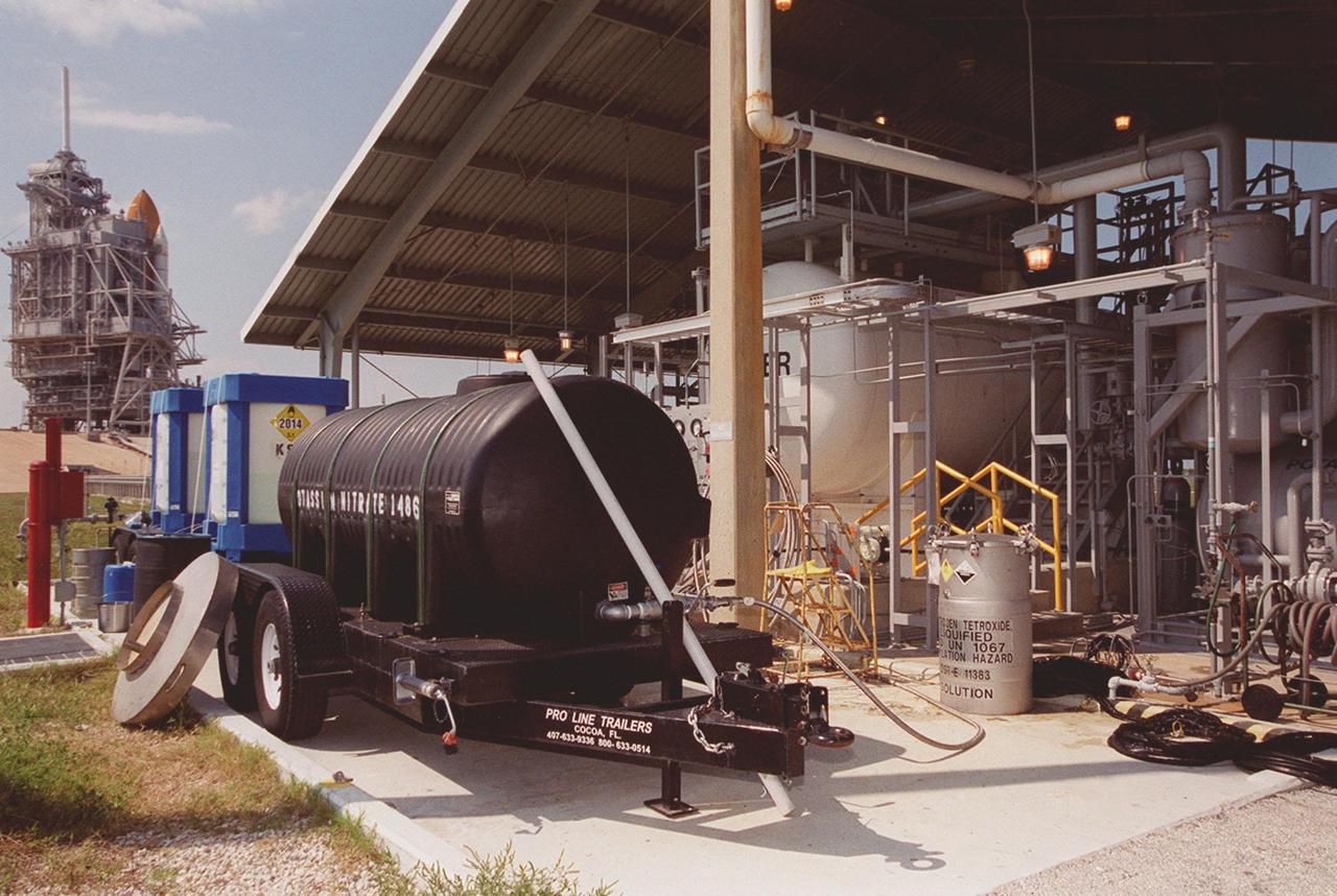 KENNEDY SPACE CENTER, FLA.  -- A recently installed fertilizer-producing system sits near Launch Pad 39A (upper left background). Using a "scrubber," the system captures nitrogen tetroxide vapor that develops as a by-product when it is transferred from ground storage tanks into the Shuttle storage tanks. Nitrogen tetroxide is used as the oxidizer for the hypergolic propellant in the Shuttle's on-orbit reaction control system. The scrubber then uses hydrogen peroxide to produce nitric acid, which, after adding potassium hydroxide, converts to potassium nitrate, a commercial fertilizer. The black tanker at left is collecting the potassium nitrate, which will be used on the orange groves that KSC leases to outside companies