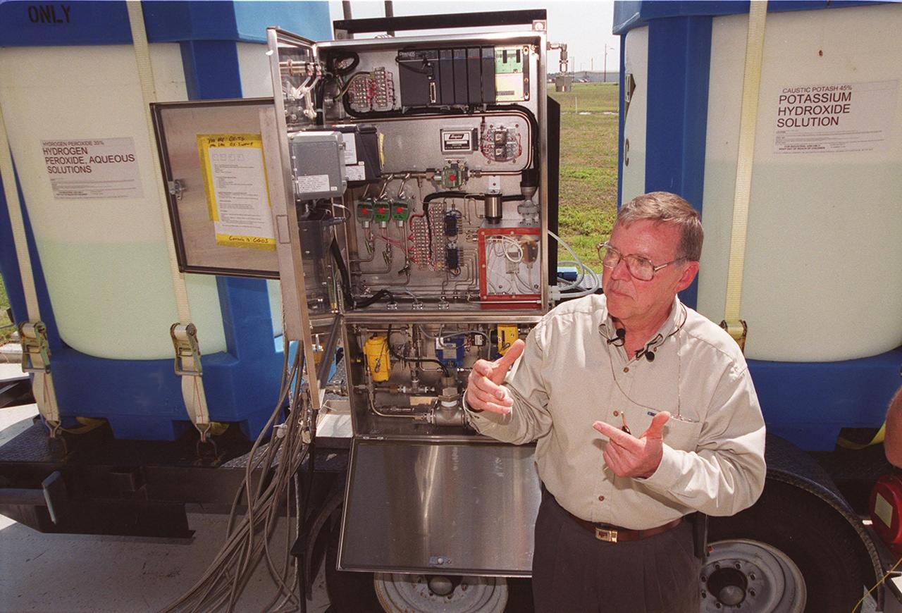 KENNEDY SPACE CENTER, FLA. -- Clyde Parrish, a NASA/KSC engineer, explains how the fertilizer scrubber control panel (center) works to turn nitrogen tetroxide vapor into fertilizer, potassium hydroxide. Parrish developed the system, which uses a "scrubber," to capture nitrogen tetroxide vapor that develops as a by-product when it is transferred from ground storage tanks into the Shuttle storage tanks. Nitrogen tetroxide is used as the oxidizer for the hypergolic propellant in the Shuttle's on-orbit reaction control system. The scrubber then uses hydrogen peroxide to produce nitric acid, which, after adding potassium hydroxide, converts to potassium nitrate. The resulting fertilizer will be used on the orange groves that KSC leases to outside companies