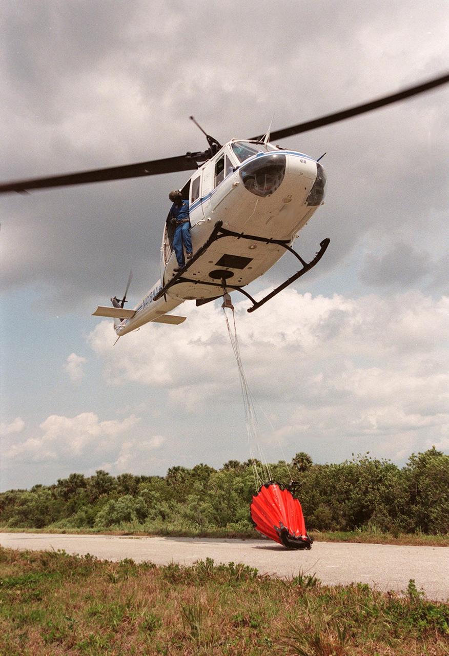 KENNEDY SPACE CENTER, FLA. -- A NASA helicopter lifts a high-impact-resistant flexible plastic bucket that will be used for fire protection on property and buildings at Kennedy Space Center. Known as the "Bambi" bucket, the 324-gallon container will also support the Fish and Wildlife Service for controlled burns plus any wild fires in the area