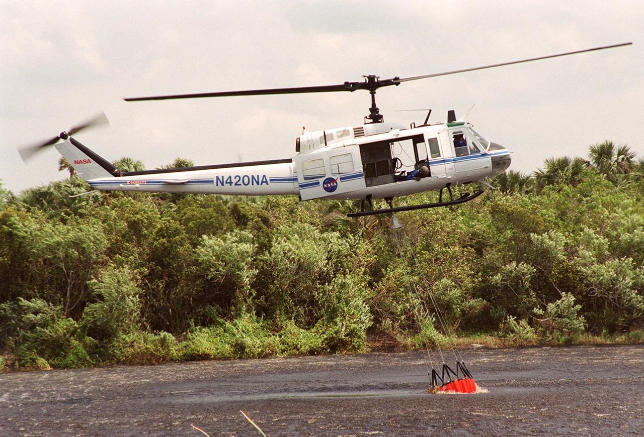 KENNEDY SPACE CENTER, FLA. -- A NASA helicopter hovers over the water while a high-impact-resistant flexible plastic bucket fills. The 324-gallon container will be used for fire protection on property and buildings at Kennedy Space Center. Known as the "Bambi" bucket, it will also support the Fish and Wildlife Service for controlled burns plus any wild fires in the area