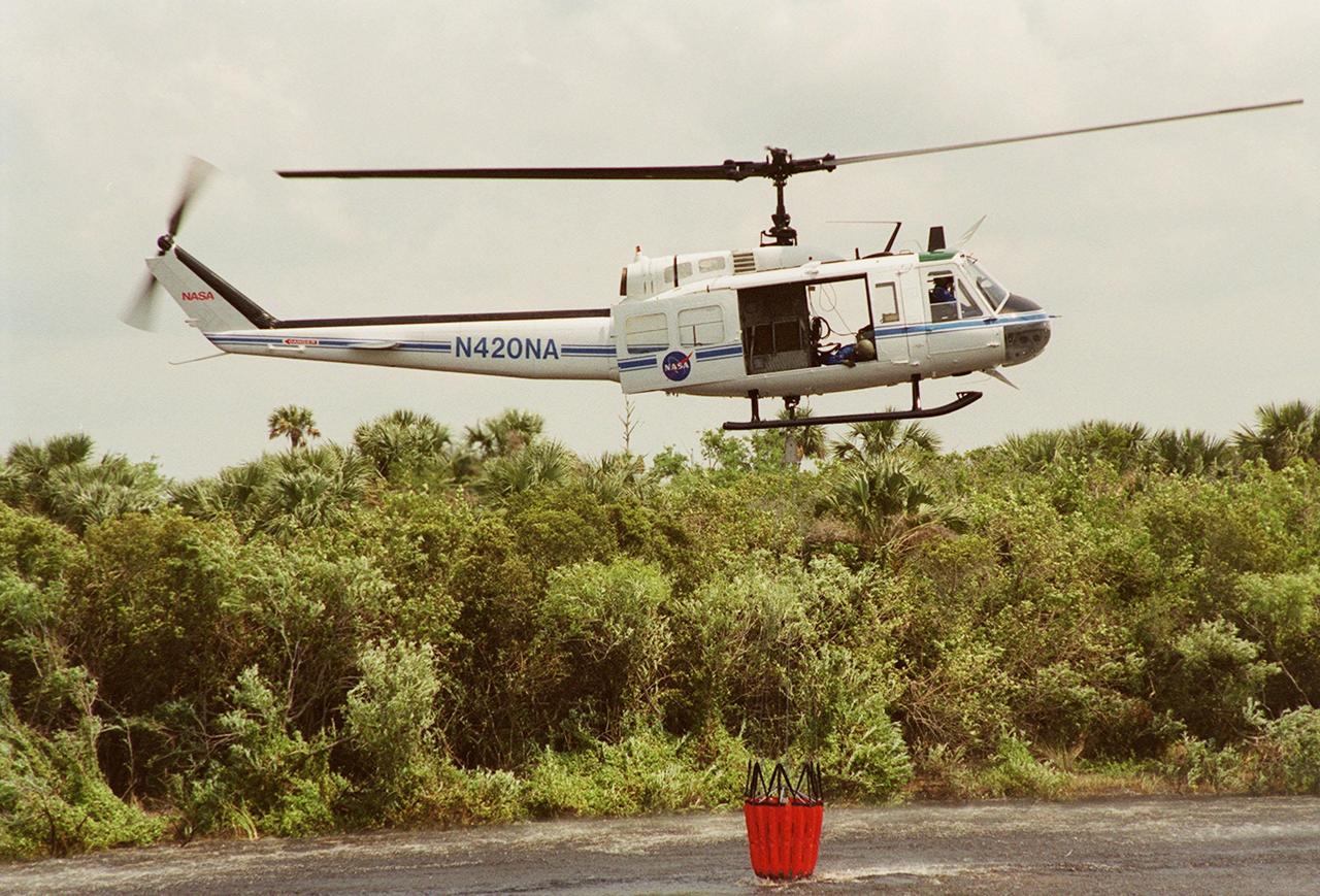 KENNEDY SPACE CENTER, FLA. -- A NASA helicopter lifts a high-impact-resistant flexible plastic bucket filled with water. The container will be used for fire protection on property and buildings at Kennedy Space Center.. Known as the "Bambi" bucket, it will also support the Fish and Wildlife Service for controlled burns plus any wild fires in the area.