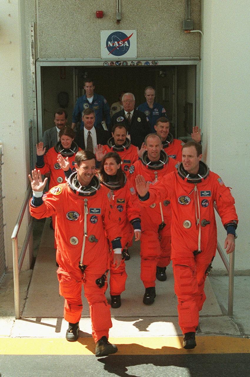 The STS-101 crew wave to onlookers as they leave the Operations and Checkout Building enroute a third time to Launch Pad 39A for launch of Space Shuttle Atlantis. The previous two launch attempts were scrubbed due to high cross winds at the Shuttle Landing Facility. They are (front) Pilot Scott J. Horowitz (left) and Commander James D. Halsell Jr.; (middle) Mission Specialists Mary Ellen Weber and Jeffrey N. Williams; (back) Mission Specialists Susan J. Helms, Yury Usachev of Russia and James S. Voss. The mission will take the crew to the International Space Station to deliver logistics and supplies and to prepare the Station for the arrival of the Zvezda Service Module, expected to be launched by Russia in July 2000. Also, the crew will conduct one space walk. This is the third assembly flight to the Space Station. After the 10-day mission, Atlantis is expected to land at KSC May 6 at about 12:03 p.m. EDT