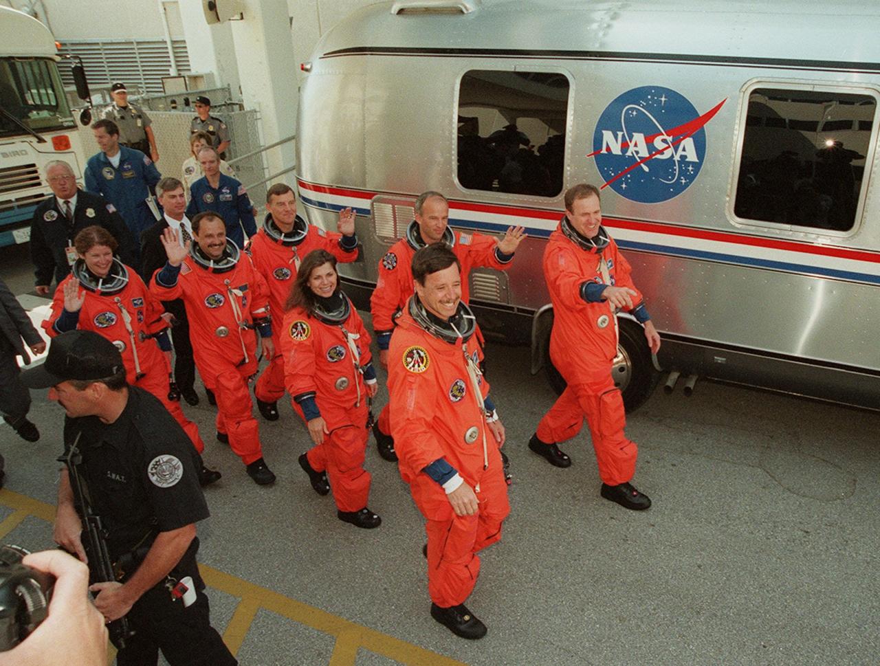 Smiling and waving to onlookers, the STS-101 crew eagerly walk to the waiting Astrovan that will take them to Launch Pad 39A a third time for launch of Space Shuttle Atlantis. From left are Mission Specialists Susan J. Helms, Yury Usachev of Russia, James S. Voss, Mary Ellen Weber and Jeffrey N. Williams; Pilot Scott J. Horowitz; and Commander James D. Halsell Jr. (pointing). The previous two launch attempts were scrubbed due to high cross winds at the Shuttle Landing Facility. The mission will take the crew to the International Space Station to deliver logistics and supplies and to prepare the Station for the arrival of the Zvezda Service Module, expected to be launched by Russia in July 2000. Also, the crew will conduct one space walk. This is the third assembly flight to the Space Station. After the 10-day mission, Atlantis is expected to land at KSC May 6 at about 12:03 p.m. EDT