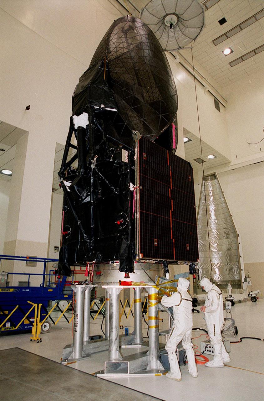 Workers in KSC’s Spacecraft Assembly and Encapsulation Facility (SAEF-2) prepare the Tracking and Data Relay Satellite (TDRS-H) above them for electrical testing. The TDRS is scheduled to be launched from CCAFS June 29 aboard an Atlas IIA/Centaur rocket. One of three satellites (labeled H, I and J) being built in the Hughes Space and Communications Company Integrated Satellite Factory in El Segundo, Calif., the latest TDRS uses an innovative springback antenna design. A pair of 15-foot-diameter, flexible mesh antenna reflectors fold up for launch, then spring back into their original cupped circular shape on orbit. The new satellites will augment the TDRS system’s existing Sand Ku-band frequencies by adding Ka-band capability. TDRS will serve as the sole means of continuous, high-data-rate communication with the space shuttle, with the International Space Station upon its completion, and with dozens of unmanned scientific satellites in low earth orbit