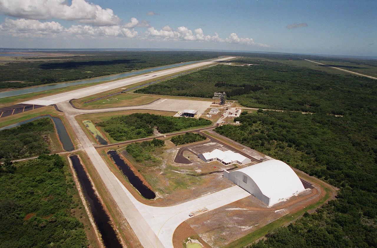 In the foreground of this aerial photo is the Reusable Launch Vehicle (RLV) Support Complex at Kennedy Space Center. At right is a multi-purpose hangar and to its left is a building for related ground support equipment and administrative/ technical support. The complex is situated at the Shuttle Landing Facility (center). At the upper left is the runway. The RLV complex will be available to accommodate the Space Shuttle; the X-34 RLV technology demonstrator; the L-1011 carrier aircraft for Pegasus and X-34; and other RLV and X-vehicle programs. The complex is jointly funded by the Spaceport Florida Authority, NASA’s Space Shuttle Program and KSC