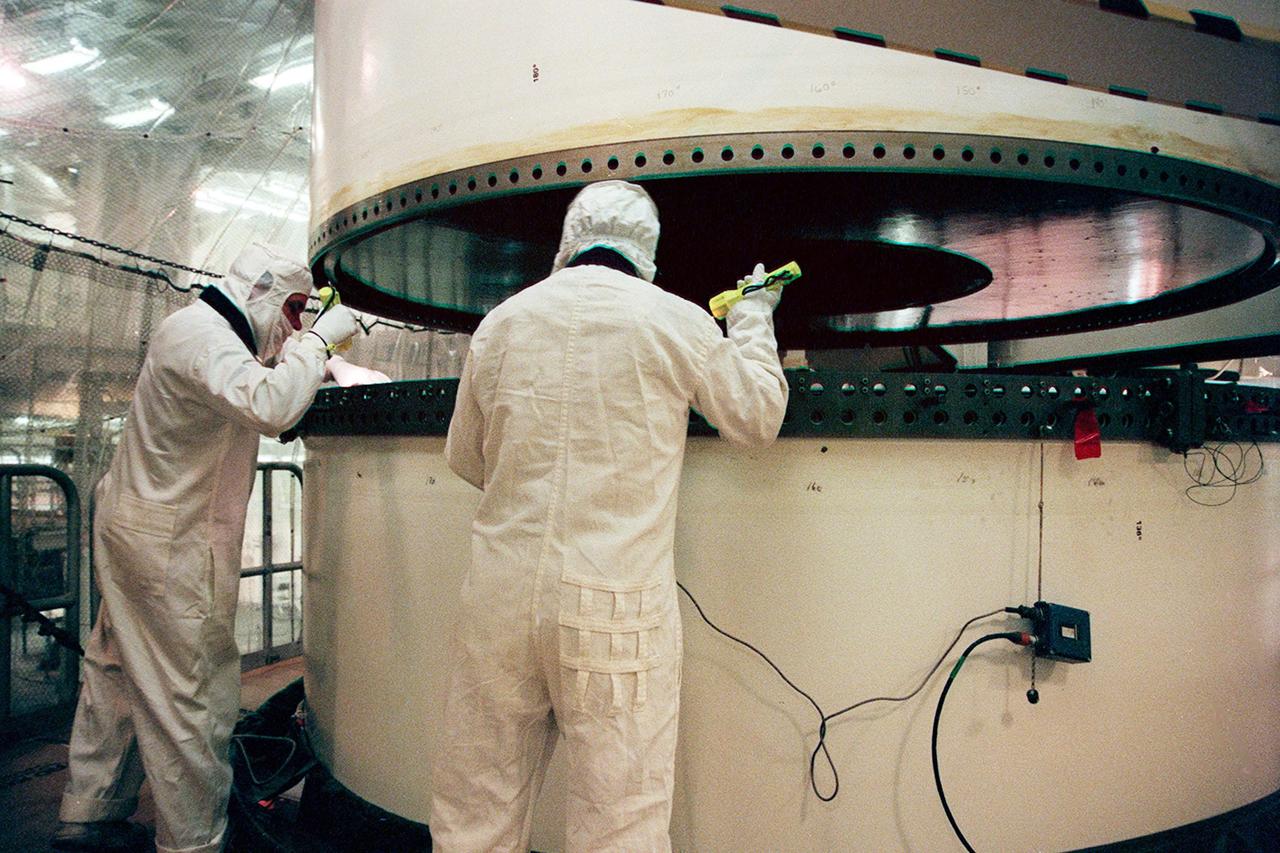 In the Vehicle Assembly Building, workers check two segments of a solid rocket booster (SRB) to be mated. The SRB is part of the stack for the STS-92 mission, scheduled for launch Oct. 5 from Launch Pad 39A