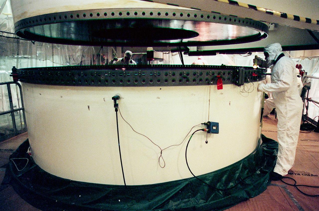 In the Vehicle Assembly Building, workers check the lower segment of a solid rocket booster (SRB) to be mated to the one above. The SRB is part of the stack for the STS-92 mission, scheduled for launch Oct. 5 from Launch Pad 39A