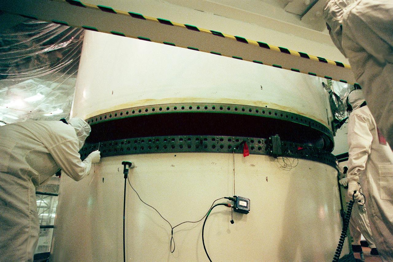 In the Vehicle Assembly Building, workers check the rings on the upper and lower segments of a solid rocket booster (SRB) before mating them. The SRB is part of the stack for the STS-92 mission, scheduled for launch Oct. 5 from Launch Pad 39A
