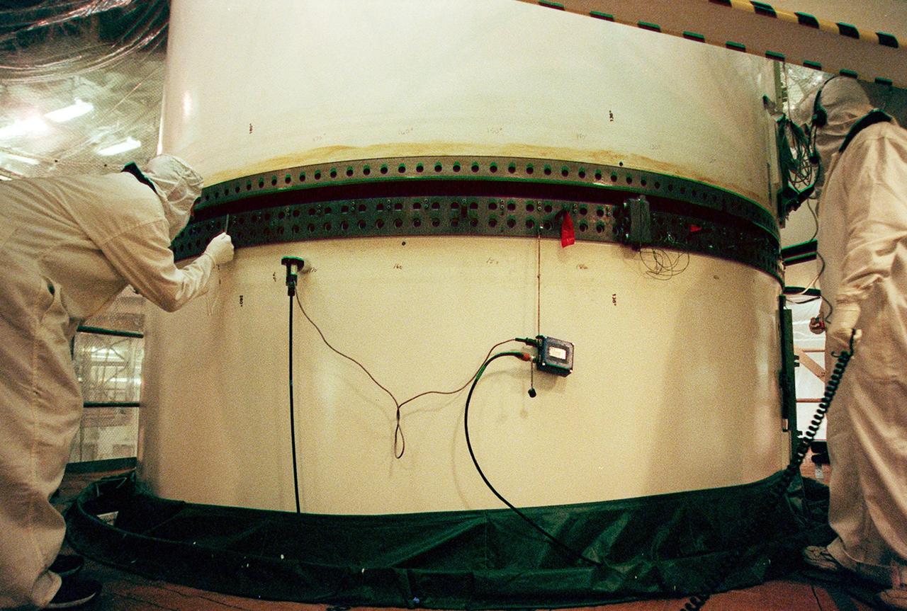 In the Vehicle Assembly Building, workers check the rings on the segments of a solid rocket booster (SRB) before mating them.; The SRB is part of the stack for the STS-92 mission, scheduled for launch Oct. 5 from Launch Pad 39A