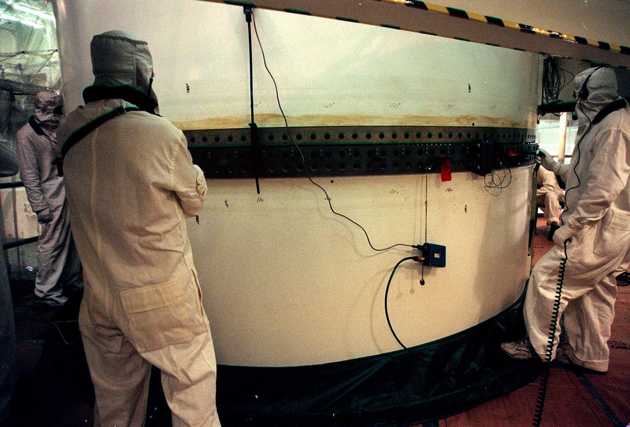 In the Vehicle Assembly Building, workers check the rings on the segments of a solid rocket booster (SRB) after mating them. The SRB is part of the stack for the STS-92 mission, scheduled for launch Oct. 5 from Launch Pad 39A