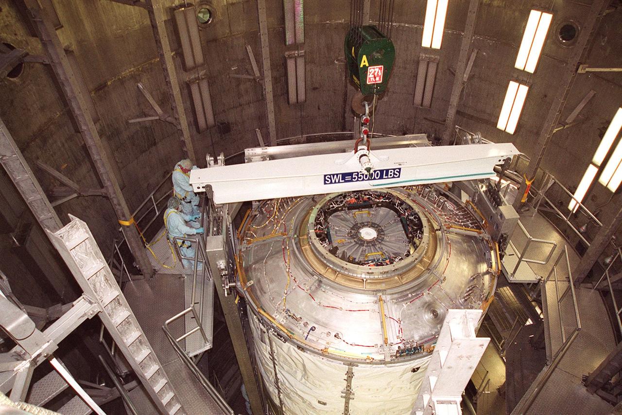 KENNEDY SPACE CENTER, FLA. -- After successfully completing a leak test inside a vacuum chamber in the Operations and Checkout Building, the U.S. Lab, a component of the International Space Station, is ready to be removed from the chamber. Workers check a crane being attached to the rotation and handling fixture that holds the Lab. The 32,000-pound scientific research lab, named Destiny, is the first Space Station element to spend seven days in the renovated vacuum chamber. Destiny is scheduled to be launched on Shuttle mission STS-98, the 5A assembly mission, targeted for Jan. 18, 2001. During the mission, the crew will install the Lab in the Space Station during a series of three space walks. The STS-98 mission will provide the Station with science research facilities and expand its power, life support and control capabilities. The U.S. Lab module continues a long tradition of microgravity materials research, first conducted by Skylab and later Shuttle and Spacelab missions. Destiny is expected to be a major feature in future research, providing facilities for biotechnology, fluid physics, combustion, and life sciences research