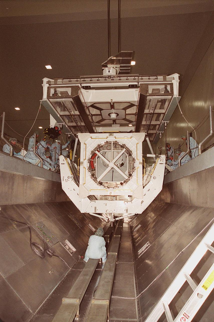 KENNEDY SPACE CENTER, FLA. -- In the Space Station Processing Facility, an overhead crane lowers the Pressurized Mating Adapter -3 (PMA-3) into a payload canister for transport to the Orbiter Processing Facility. Workers at the sides and below watch the process. The PMA-3, a component of the International Space Station, is part of the payload on Space Shuttle mission STS-92, scheduled to launch Oct. 5. The mission will be the fifth flight to the Space Station, and the 100th Shuttle flight overall. PMA-3 provides shuttle docking port for solar array installation on flight 4A (mission STS-97 scheduled for Nov. 30), and Lab installation on flight 5A (mission STS-98, scheduled for Jan. 18, 2001)