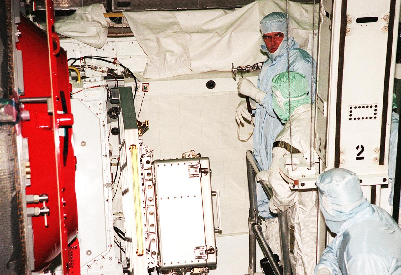 KENNEDY SPACE CENTER, FLA. -- STS-92 Mission Specialist Bill McArthur (with tool in hand) gets a close look at the Pressurized Mating Adapter-3 (PMA-3) in the payload bay of orbiter Discovery. He and other crew members Commander Brian Duffy, Pilot Pam Melroy and Mission Specialists Koichi Wakata, Leroy Chiao, Jeff Wisoff, and Michael Lopez-Alegria are at KSC to take part in Crew Equipment Interface Test activities. Discovery is in the Orbiter Processing Facility bay 1. STS-92 is scheduled to launch Oct. 5 on Shuttle Discovery from Launch Pad 39A on the fifth flight to the International Space Station. Discovery will carry the Integrated Truss Structure (ITS) Z1, the PMA-3, Ku-band Communications System, and Control Moment Gyros (CMGs