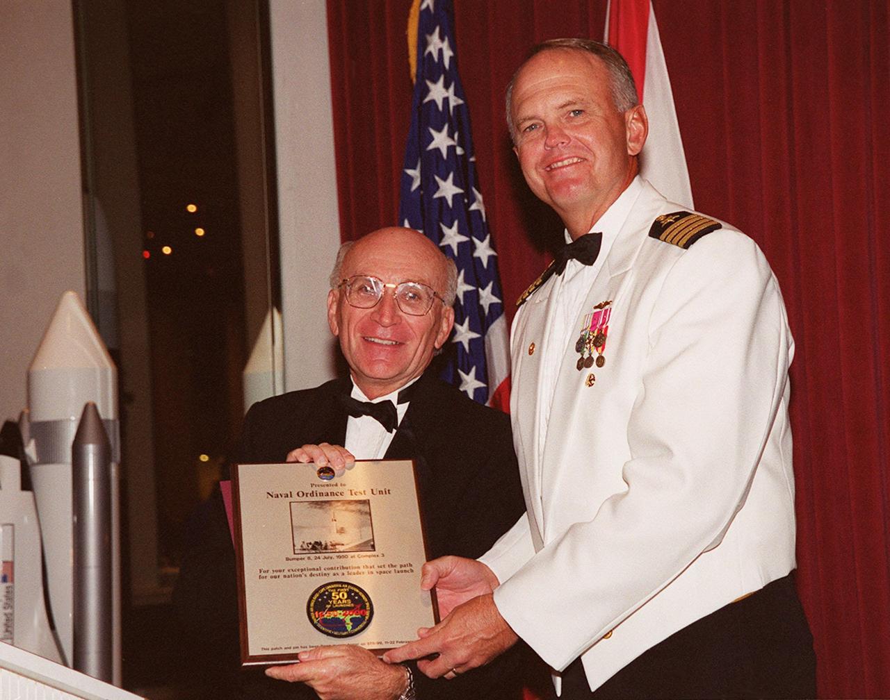 At the 50th anniversary gala that capped a year-long celebration of 50 years of rocket launches from Cape Canaveral Air Force Station, gala chairman Ed Gormel (left) presents a plaque to Capt. Harry Sheffield, Commander, Naval Ordnance Test Unit, Cape Canaveral. The first launch at CCAFS took place at 9:28 a.m. on July 24, 1950, with the liftoff of Bumper 8 from Launch Complex 3. The gala was hosted by the Cape Canaveral Chapter Air Force Association