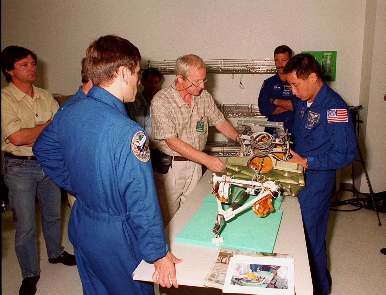 KENNEDY SPACE CENTER, FLA. -- During Crew Equipment Interface Test (CEIT) activities at SPACEHAB, members of the STS-106 crew check out a Russian foot restraint, equipment that will be part of the payload on their mission to the International Space Station. Around the table are Mission Specialist Yuri I. Malenchenko (back to camera), a SPACEHAB worker, and Mission Specialists Daniel C. Burbank (at end of table) and Edward T. Lu (right). Others at KSC for the CEIT are Commander Terrence W. Wilcutt, Pilot Scott D. Altman, and Mission Specialists Boris V. Morukov and Richard A. Mastracchio. Malenchenko and Morukov represent the Russian Aviation and Space Agency. On the 11-day mission, the seven-member crew will perform support tasks on orbit, transfer supplies and prepare the living quarters in the newly arrived Zvezda Service Module for the first long-duration crew, dubbed “Expedition One,” which is due to arrive at the Station in late fall. STS-106 is scheduled to launch Sept. 8, 2000, at 8:31 a.m. EDT from Launch Pad 39B