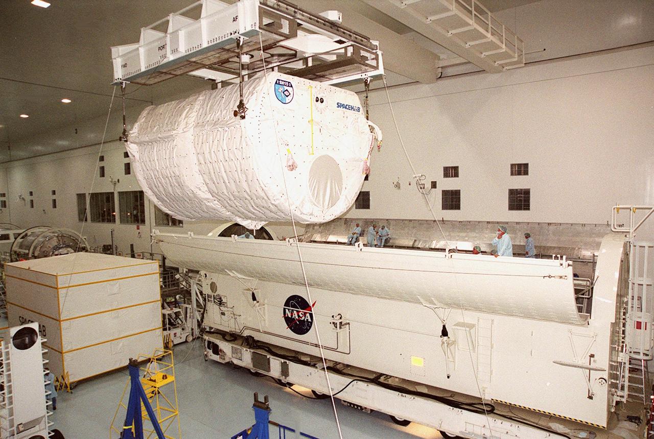 KENNEDY SPACE CENTER, FLA. -- The SPACEHAB module is moved toward the payload canister (right) that will transport it to the launch pad. STS-106 is scheduled to launch Sept. 8 at 8:31 a.m. EDT. During the mission, to the International Space Station, the crew will complete service module support tasks on orbit, transfer supplies and outfit the Space Station for the first long-duration crew. Workers attach an overhead crane to the SPACEHAB module to lift it off the transport vehicle beneath it. The module, part of the payload on mission STS-106, will be placed in the payload canister for transport to the launch pad. STS-106 is scheduled to launch Sept. 8 at 8:31 a.m. EDT