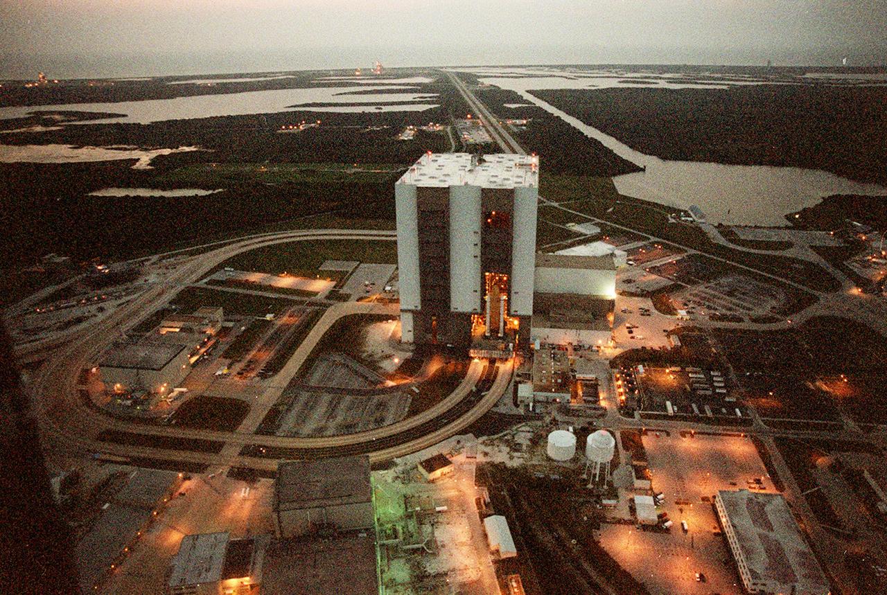 KENNEDY SPACE CENTER, FLA. -- At 6:30 a.m. EDT an aerial view captures a first in Space Shuttle history: a fully stacked Shuttle - Atlantis - is rolling into the Vehicle Assembly Building's (VAB) high bay 2 on the building's west side (center of photo).  The VAB and nearby rock-paved crawlerway (circling to the left) have recently undergone major modifications to provide Shuttle fliglht hardware more storage space and protection - "Safe Haven" - from hurricanes or tropical storms.  Atlantis, the twin solid rocket boosters and external tank begain moving out of VAB high bay 1 on the east side at 2:59 a.m. EDT.  The 6-million pound crawler transporter carried the Mobile Launcher Platform and Space Shuttle around the north side of the VAB and into high bay 2.  To the right of the VAB is the turn basin.  In the background can be seen both Launch Pads with the Atlantic Ocean behind them.  After the successful "Safe Haven" fit check, Shuttle Atlantis is scheduled to roll out to Launch Pad 39B in preparation for the STS-106 launch on Sept. 8.