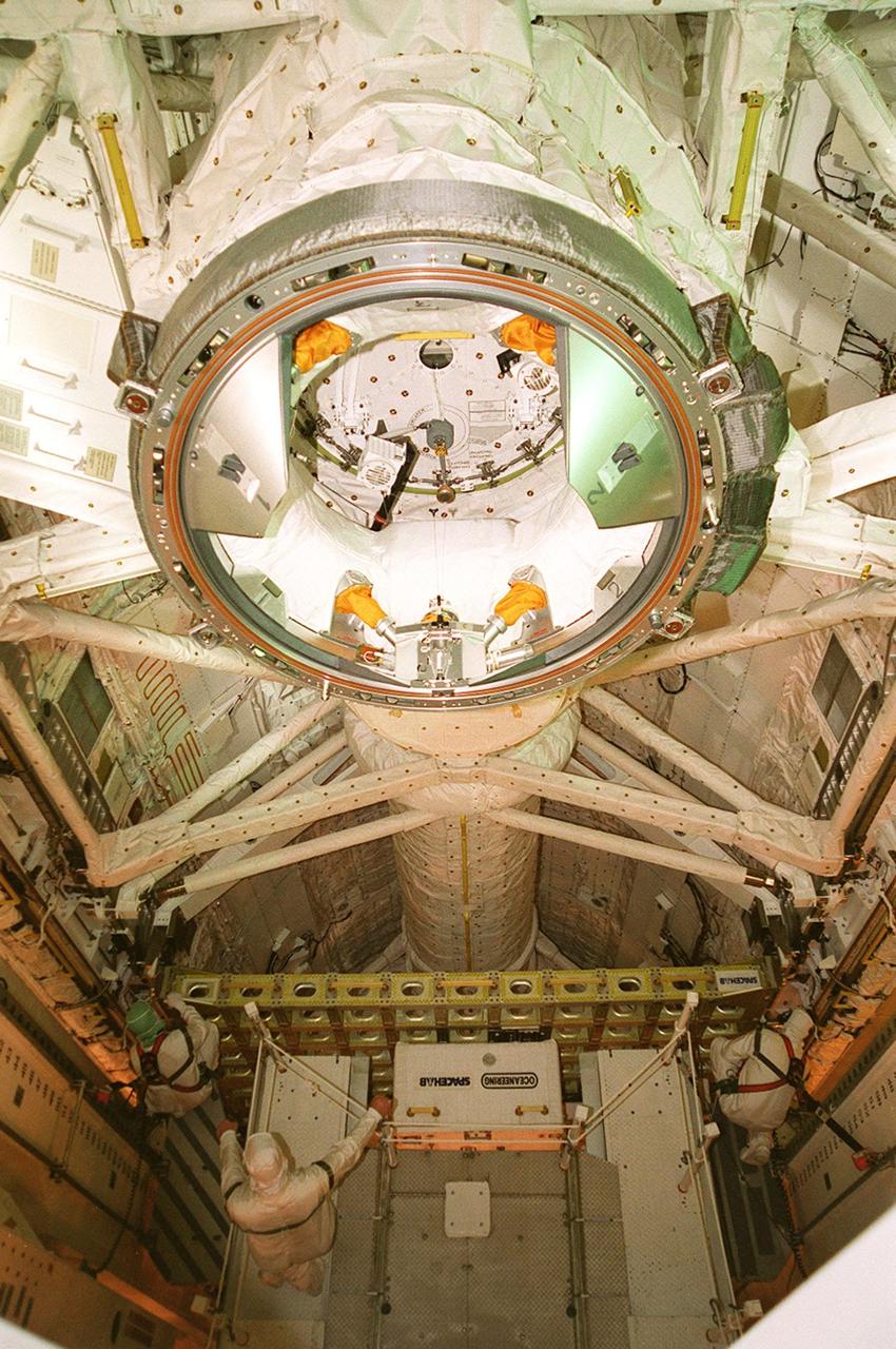 KENNEDY SPACE CENTER, FLA. -- Technicians facilitate the transfer the STS-106 payload to Atlantis on Launch Pad 39-B using the Payload Ground Handling Mechanism (PGHM). The circular structure shown is the docking adapter. The PGHM (pronounced pigem) is located inside the Payload Changeout Room (PCR) of each shuttle launch pad’s Rotating Service Structure. The PGHM removes payloads from a transportation canister and installs them into the orbiter. It is essentially NASA’s largest fork-lift