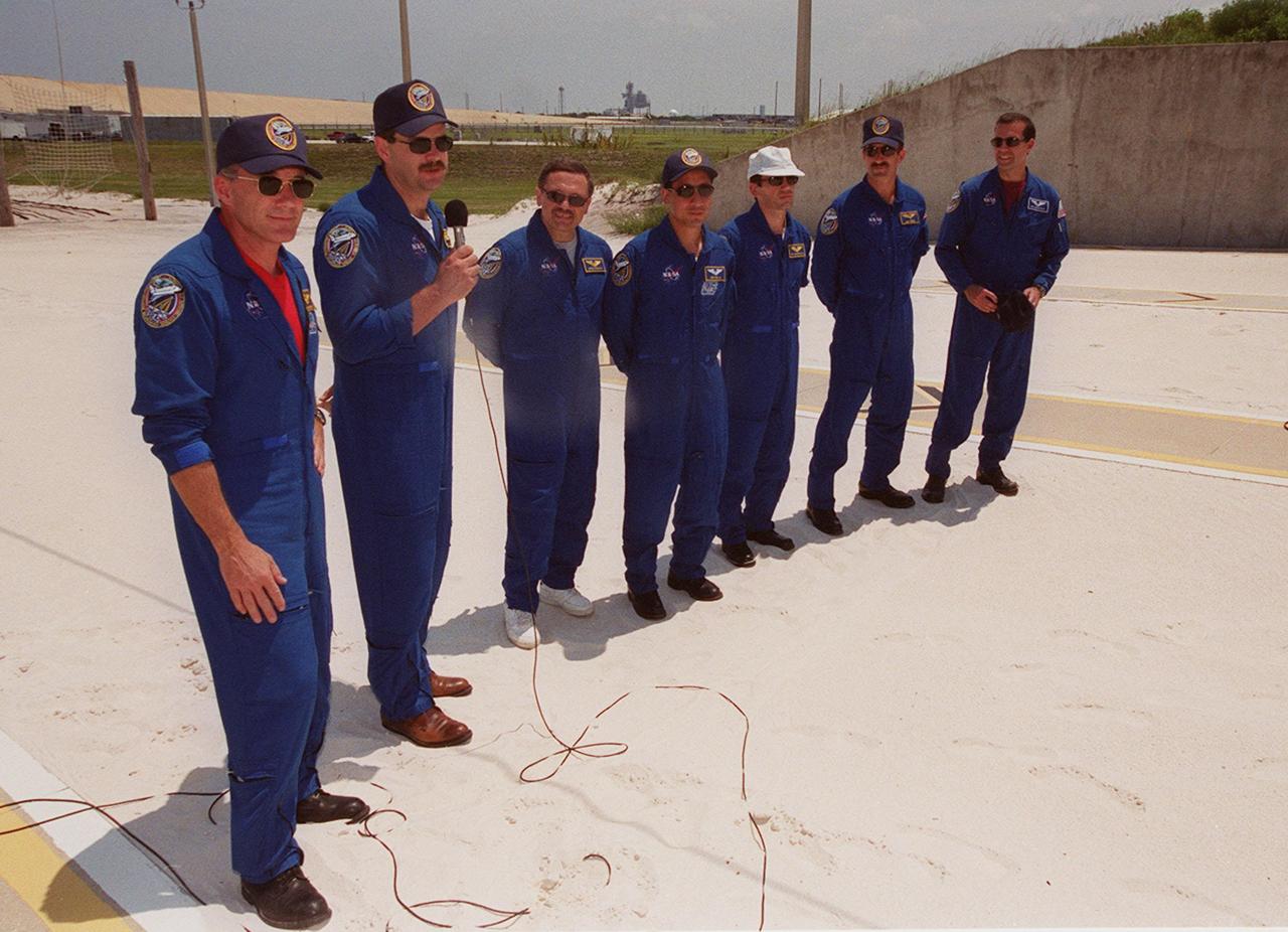 KENNEDY SPACE CENTER, Fla.  -- STS-106 Pilot Scott D. Altman, left of STS-106 Commander Terrence W. Wilcutt, answers a question during a press conference at the slide wire basket area of Launch Pad 39-B. Other crew members pictured are, from left, Mission Specialists Boris V. Morukov, Edward T. Lu, Yuri I. Malenchenko, Daniel C. Burbank and Richard A. Mastracchio. Malenchenko and Morukov are with the Russian Aviation and Space Agency. The flight crew were at Kennedy Space Center to take part in Terminal Countdown Demonstration Test (TCDT) activities. The TCDT provides the crew with emergency egress training and opportunities to inspect their mission payload in the orbiter’s payload bay. STS-106 is scheduled to launch Sept. 8, 2000, at 8:31 a.m. EDT from Launch Pad 39B. On the 11-day mission, the seven-member crew will perform support tasks on orbit, transfer supplies and prepare the living quarters in the newly arrived Zvezda Service Module. The first long-duration crew, dubbed “Expedition One,” is due to arrive at the Station in late fall