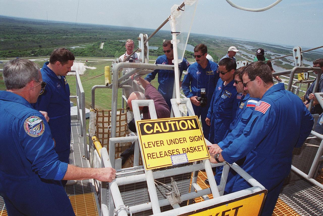 KENNEDY SPACE CENTER, Fla. -- The STS-106 flight crew review the slide wire basket egress system at Launch Pad 39-B. Pictured from left are Commander Terrence W. Wilcutt, Mission Specialists Boris V. Morukov, Richard A. Mastracchio, Daniel C. Burbank, Edward T. Lu, Yuri I. Malenchenko and Pilot Scott D. Altman. Malenchenko and Morukov are with the Russian Aviation and Space Agency. The flight crew were at Kennedy Space Center to take part in Terminal Countdown Demonstration Test (TCDT) activities. The TCDT provides the crew with emergency egress training and opportunities to inspect their mission payload in the orbiter’s payload bay. STS-106 is scheduled to launch Sept. 8, 2000, at 8:31 a.m. EDT from Launch Pad 39B. On the 11-day mission, the seven-member crew will perform support tasks on orbit, transfer supplies and prepare the living quarters in the newly arrived Zvezda Service Module. The first long-duration crew, dubbed “Expedition One,” is due to arrive at the Station in late fall