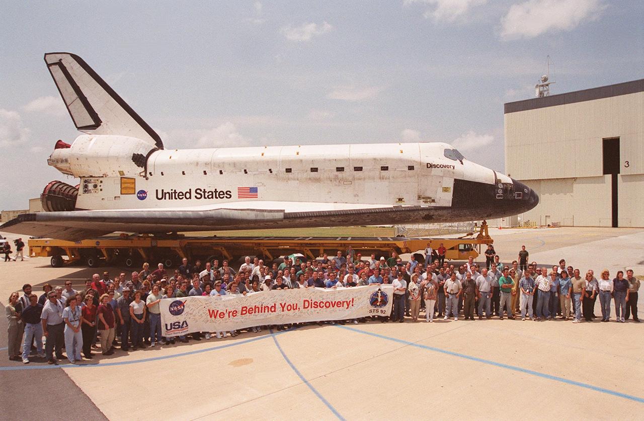 KENNEDY SPACE CENTER, FLA. -- United Space Alliance workers who worked on the orbiter Discovery during process flow pose alongside it during the orbiter’s transfer to Orbiter Processing Facility (OPF) bay 3. Ongoing payload and ground processing assessments will be completed in bay 3. Managers will then determine when to roll the orbiter to the Vehicle Assembly Building for stacking with the external tank and solid rocket boosters, and when to roll out to Launch Pad 39A. Discovery is scheduled to launch Oct. 5 at 9:30 p.m. EDT on mission STS-92, which will be the 100th flight in the Shuttle program