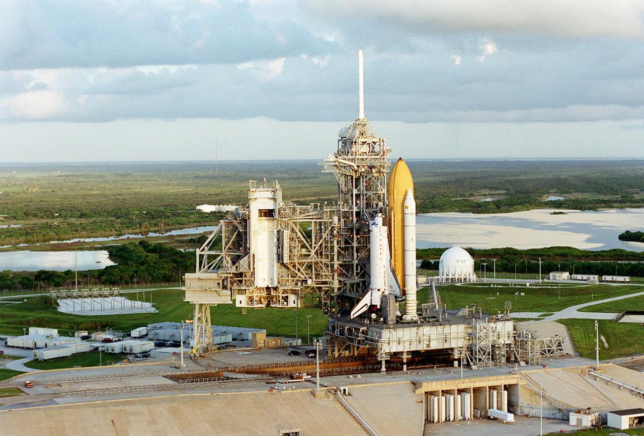 KENNEDY SPACE CENTER, Fla. --  In this aerial view, Space Shuttle Discovery is seen on Launch Pad 39A, waiting for launch on mission STS-92 Oct. 5, 2000. The opened Rotating Service Structure to the left shows the vertical passage used to lift payload canisters to the Payload Changeout Room for transfer of the payload to the orbiter. The white area at left on the ground is the slidewire basket field. The slidewire baskets are part of the emergency egress system from the orbiter. On the distant horizon is the Atlantic Ocean