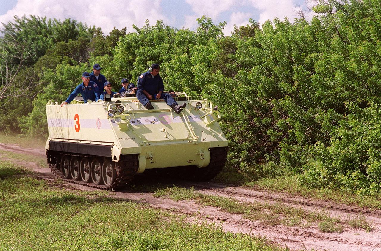 With Capt. George Hoggard, trainer with the KSC Fire Department, riding on top, Mission Specialist Koichi Wakata of Japan practices driving the M-113, part of emergency egress training during Terminal Countdown Demonstration Test (TCDT) activities. Riding in the back (on the left) are other crew members, waiting their turn to drive. The tracked vehicle could be used by the crew in the event of an emergency at the pad during which the crew must make a quick exit from the area. The TCDT also provides simulated countdown exercises and opportunities to inspect the mission payloads in the orbiter’s payload bay. STS-92 is scheduled to launch Oct. 5 at 9:30 p.m. EDT on the fifth flight to the International Space Station. It will carry two elements of the Space Station, the Integrated Truss Structure Z1 and the third Pressurized Mating Adapter. The mission is also the 100th flight in the Shuttle program