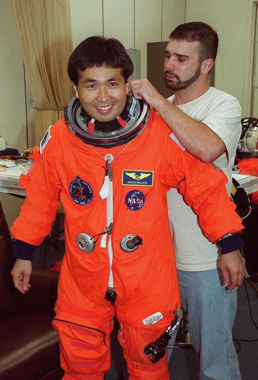During pre-pack and fit check in the Operations and Checkout Building, STS-92 Mission Specialist Koichi Wakata of Japan gets an adjustment on his launch and entry suit. This mission is Wakata’s second Shuttle flight. He and the rest of the crew are at KSC for Terminal Countdown Demonstration Test activities. The TCDT provides emergency egress training, simulated countdown exercises and opportunities to inspect the mission payload. STS-92 is scheduled to launch Oct. 5 at 9:38 p.m. EDT from Launch Pad 39A on the fifth flight to the International Space Station. It will carry two elements of the Space Station, the Integrated Truss Structure Z1 and the third Pressurized Mating Adapter. The mission is also the 100th flight in the Shuttle program
