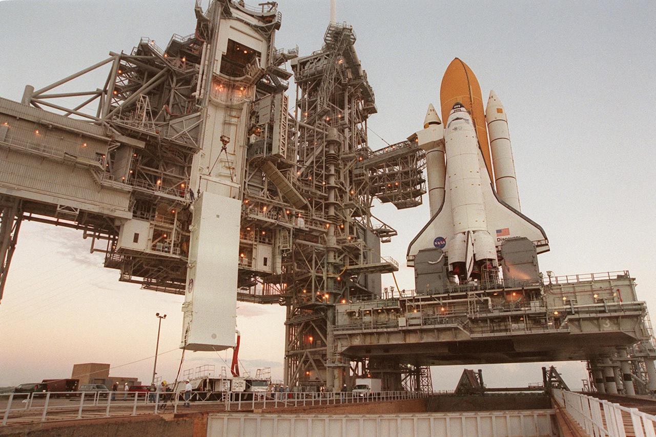 KENNEDY SPACE CENTER, Fla. --  As the sky grows lighter, , the payload canister (left) with the Integrated Truss Structure Z1 inside is slowly lifted up the side of the Rotating Service Structure to the Payload Changeout Room. There the Z1 truss will be removed and later transferred to Space Shuttle Discovery’s payload bay. The Z1 truss is the first of 10 that will become the backbone of the International Space Station, eventually stretching the length of a football field. Along with its companion payload, the third Pressurized Mating Adapter, the Z1 is scheduled to be launched aboard Discovery Oct. 5 at 9:38 p.m. EDT