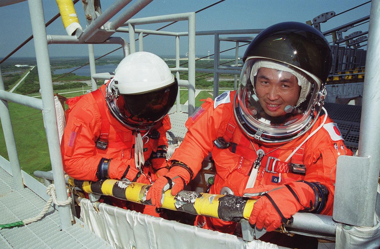 KENNEDY SPACE CENTER, FLA. -- On the 195-foot level of the Fixed Service Structure on Launch Pad 39A, STS-92 Mission Specialists William S. McArthur Jr. (left) and Koichi Wakata of Japan test the slidewire basket that they are in. They and other crew members are taking part in emergency egress training, one of the Terminal Countdown Demonstration Test activities that also include a simulated countdown. STS-92 is scheduled to launch Oct. 5 at 9:38 p.m. EDT on the fifth flight to the International Space Station. It will carry two elements of the Space Station, the Integrated Truss Structure Z1 and the third Pressurized Mating Adapter. The mission is also the 100th flight in the Shuttle program