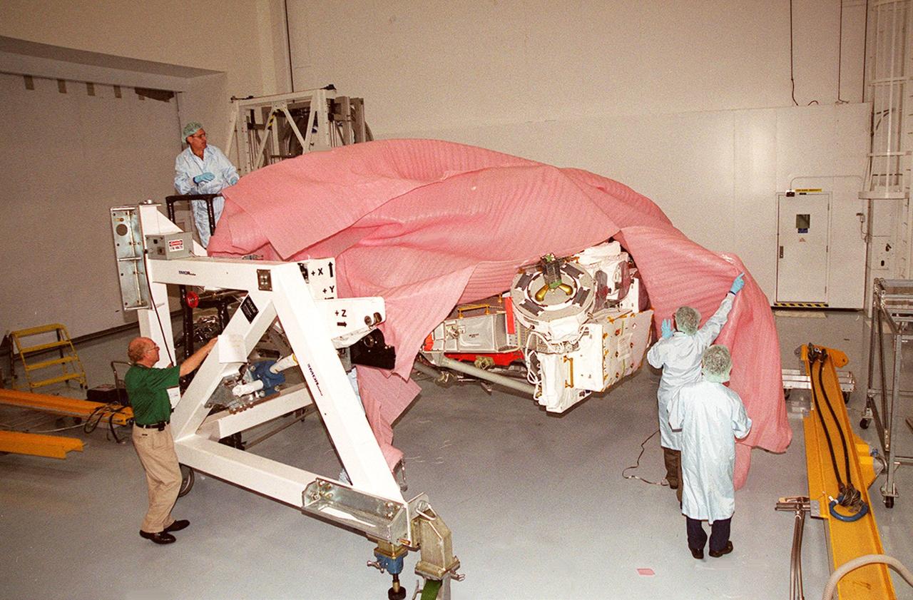KENNEDY SPACE CENTER, FLA. -- Workers in the Space Station Processing Facility remove a cover from the Mobile Remote Servicer Base System (MBS), part of the Canadian Space Agency’s (CSA) Space Station Remote Manipulator System (SSRMS). The MBS is scheduled to be launched in February 2002 on flight UF-2 to the International Space Station. The MBS will complete the Canadian Mobile Servicing System, or MSS. The mechanical arm will have the capability to "inchworm" from the U.S. Lab fixture to the MSS and travel along the Truss to work sites on the Space Station