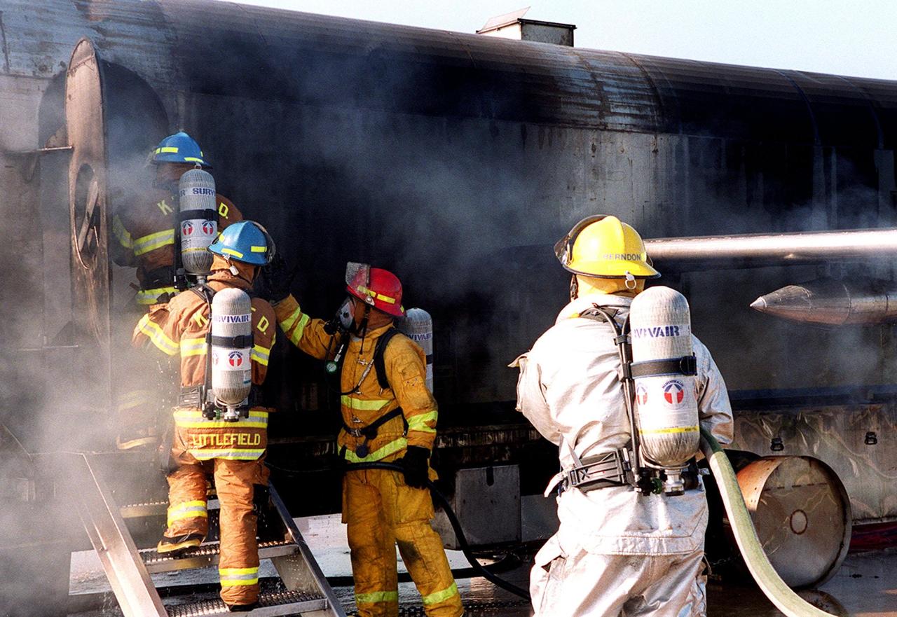 KENNEDY SPACE CENTER, FLA. --  A firefighter (right) holds a water hose in readiness as others enter a smoke-filled simulated aircraft. The activities are part of fire training exercises at Cape Canaveral Air Force Station Pad 30 for firefighters with Fire and Emergency Services at the Naval Station Mayport, Fla. The firefighters have already extinguished flames from the aircraft