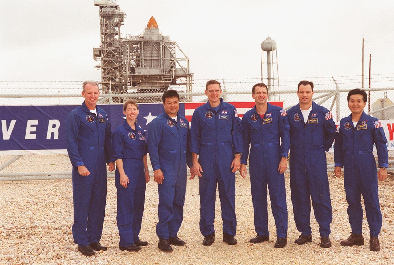 KENNEDY SPACE CENTER, Fla. --  The STS-92 crew gather outside the gate to Launch Pad 39A where Space Shuttle Discovery waits in the background for liftoff Oct. 5 at 9:38 p.m. EDT. From left to right are Commander Brian Duffy, Pilot Pamela Ann Melroy, and Mission Specialists Leroy Chiao, William S. McArthur Jr., Peter J.K. “Jeff” Wisoff, Michael E. Lopez-Alegria and Koichi Wakata of Japan. The mission payload includes Integrated Truss Structure Z-1, an early exterior framework to allow the first U.S. solar arrays on a future flight to be temporarily installed on Unity for early power; Ku-band communication to support early science capability and U.S. television; and the third Pressurized Mating Adapter to provide a Shuttle docking port for solar array installation on the sixth ISS flight and Lab installation on the seventh ISS flight. The 11-day mission will include four spacewalks