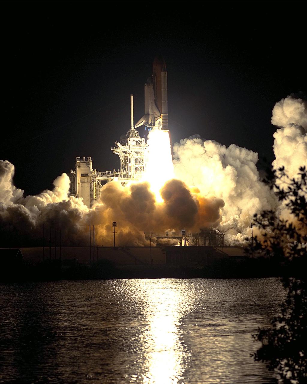 KENNEDY SPACE CENTER, Fla. -- Space Shuttle Discovery seems to burst forth from a pillow of smoke as it lifts off from Launch Pad 39A on mission STS-92 to the International Space Station. The brilliant light from the solid rocket booster flames is reflected in nearby water. The perfect on-time liftoff occurred at 7:17 p.m. EDT, sending a crew of seven on the 100th launch in the history of the Shuttle program. Discovery carries a payload that includes the Integrated Truss Structure Z-1, first of 10 trusses that will form the backbone of the Space Station, and the third Pressurized Mating Adapter that will provide a Shuttle docking port for solar array installation on the sixth Station flight and Lab installation on the seventh Station flight. Discovery’s landing is expected Oct. 22 at 2:10 p.m. EDT
