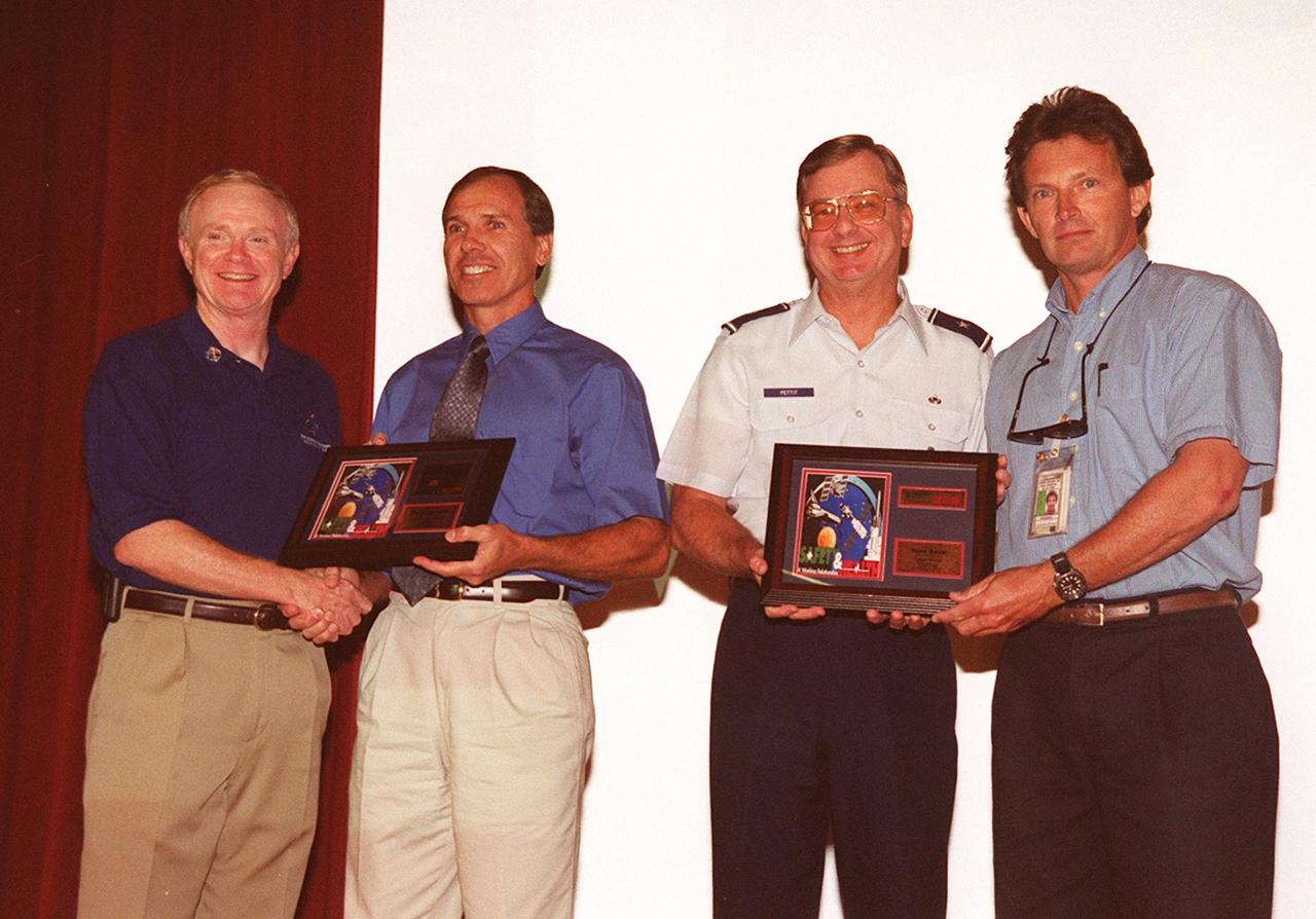 During Super Safety and Health Day at KSC, two employees were recognized for submitting winning entries in the theme and logo/poster contests. At left, Center Director Roy Bridges congratulates Dave Earhart with United Space Alliance (USA) for his winning logo; at right, Brig. Gen. Ronald D. Pettit congratulates David Koval with Space Gateway Support (SGS) for his winning theme, “Safety and Health: A Working Relationship.” Safety Day is a full day of NASA-sponsored, KSC and 45th Space Wing events involving a number of health and safety related activities: Displays, vendors, technical paper sessions, panel discussions, a keynote speaker, etc. The entire Center and Wing stand down to participate in the planned events. Safety Day is held annually to proactively increase awareness in safety and health among the government and contractor workforce population. The first guiding principle at KSC is “Safety and Health First.” KSC’s number one goal is to “Assure sound, safe and efficient practices and processes are in place for privatized/commercialized launch site processing.