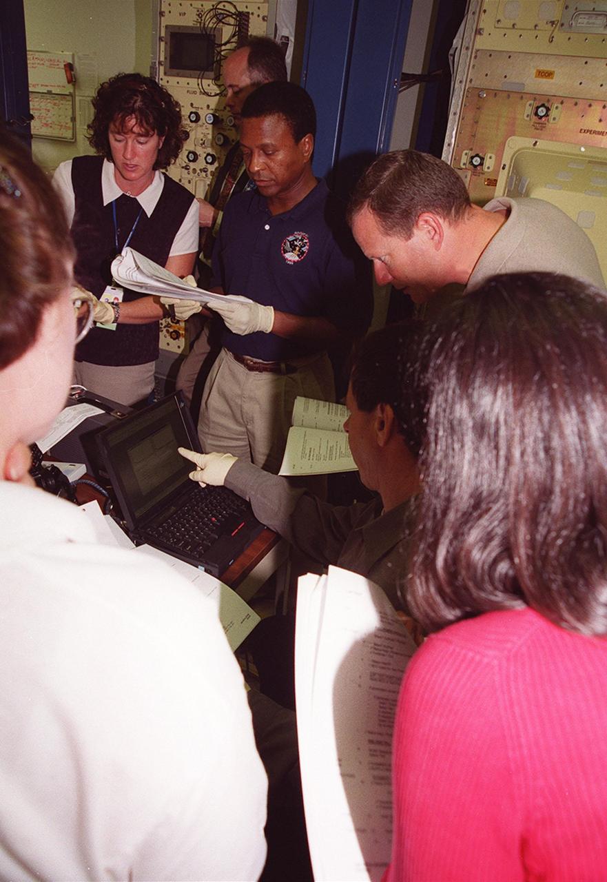 KENNEDY SPACE CENTER, FLA. -- At SPACEHAB, STS-107 crew members refer to documentation while Mission Specialist Ilan Ramon of Israel points to data on a laptop screen. Gathered around Ramon are (left to right) Mission Specialists Laurel Clark, Michael Anderson, David Brown and Kalpana Chawla (back to camera). Identified as a research mission, STS-107 is scheduled for launch July 19, 2001