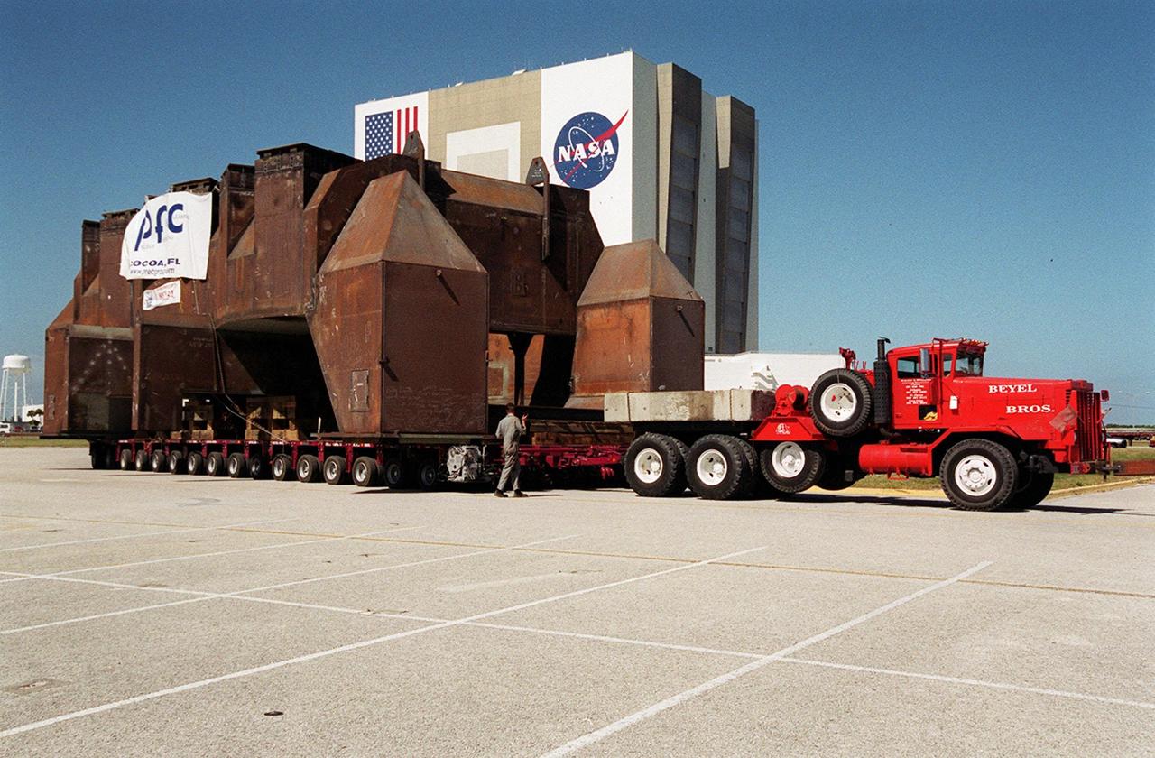 Looking somewhat like a medieval building, this launch table was built in support of the Delta Evolved Expendable Launch Vehicle (EELV) program, known as Delta IV. Fabricated by Jered Industries in Georgia, it was floated on a barge down the Intercoastal Waterway, through the Barge Canal to the turn basin in the Launch Complex 39 Area. In the background is the Vehicle Assembly Building. The table is approximately 70 feet long, 40 feet wide and 50 feet high, and weighs about 600,000 pounds. It is being transferred to Launch Complex 37B, Cape Canaveral Air Force Station, the site of the Delta IV launch complex under construction. Accompanying the launch table on the barge are flame deflectors, which are also to be erected on pad 37B
