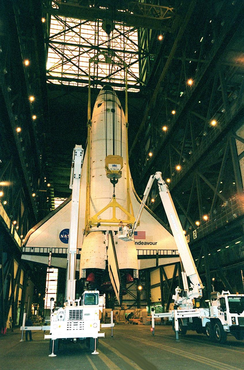 KENNEDY SPACE CENTER, FLA. -- As the orbiter Endeavour hangs suspended from a crane inside the Vehicle Assembly Building, workers make adjustments on it before it is lifted and stacked with its external tank and solid rocket boosters. The stack is in high bay 1. Space Shuttle Endeavour is scheduled to be launched Nov. 30 on mission STS-97, the sixth construction flight to the International Space Station