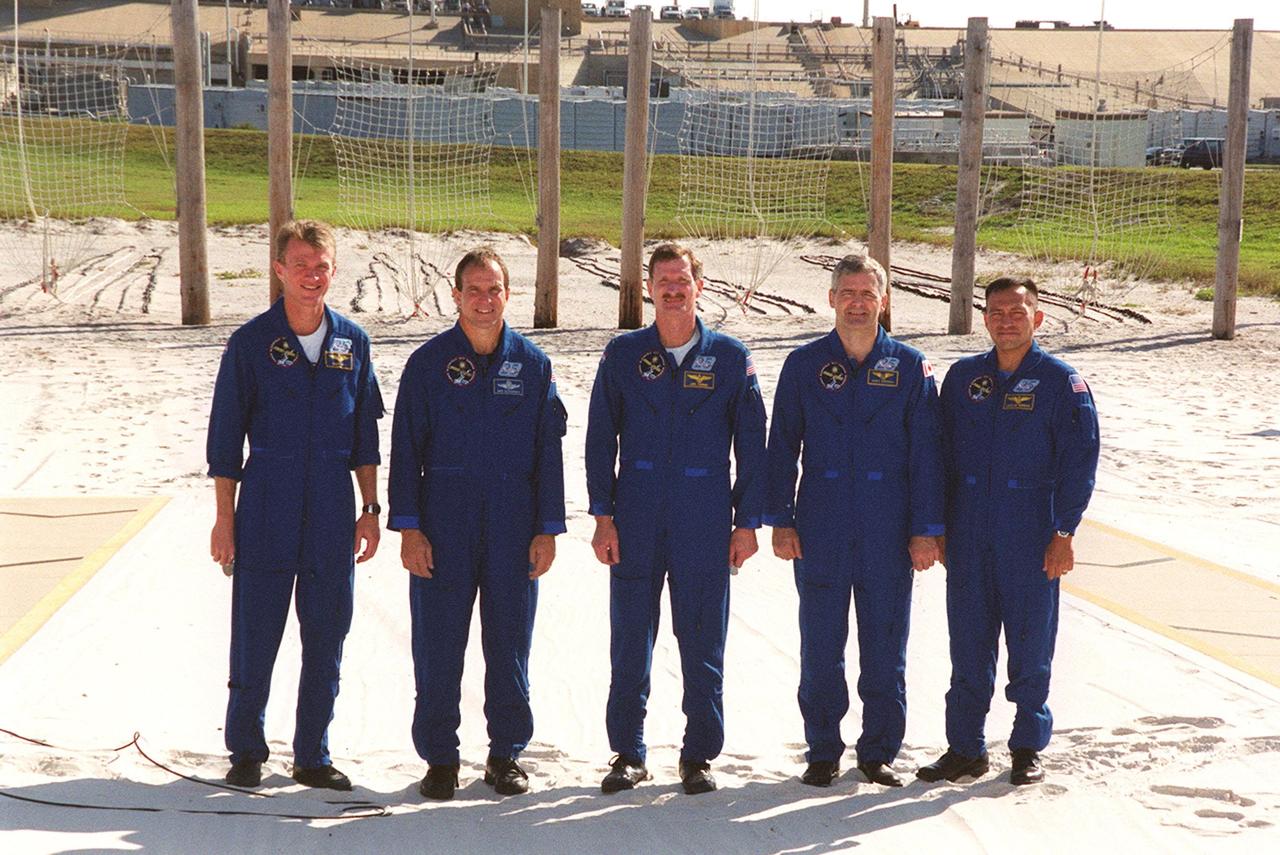 Standing in the slidewire landing zone at Launch Pad 39B, the STS-97 crew respond to questions from the media. They are, left to right, Commander Brent Jett, Pilot Mike Bloomfield and Mission Specialists Joe Tanner, Marc Garneau and Carlos Noriega. Garneau is with the Canadian Space Agency. The nets suspended behind them are a braking system catch net for the slidewire baskets that provide emergency exit from the orbiter and Fixed Service Structure. The crew is at KSC to take part in Terminal Countdown Demonstration Test activities that include emergency egress training, familiarization with the payload, and a simulated launch countdown. Mission STS-97is the sixth construction flight to the International Space Station. Its payload includes the P6 Integrated Truss Structure and a photovoltaic (PV) module, with giant solar arrays that will provide power to the Station. The mission includes two spacewalks to complete the solar array connections. STS-97 is scheduled to launch Nov. 30 at 10:05 p.m. EST