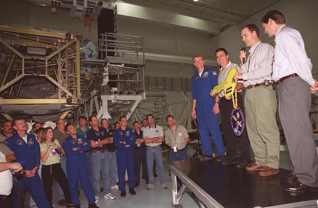 Boeing workers officially turn over the P6 Integrated Truss Structure to the NASA shuttle integration team in a ceremony in the Space Station Processing Facility. A symbolic key will be presented to Brent Jett (at left), commander on mission STS-97, which is taking the P6 to the International Space Station. Next to Jett are (left to right) Bill Dowdell, mission manager; Mark Sorensen, outboard truss cargo element manager for Boeing; and John Elbon, Boeing ISS director of ground operations at KSC. Among the attendees at left watching the ceremony are other STS-97 crew members (in uniform, from left) Mission Specialists Joe Tanner and Carlos Noriega and Pilot Mike Bloomfield. Mission STS-97is the sixth construction flight to the International Space Station. Its payload includes a photovoltaic (PV) module, with giant solar arrays that will provide power to the Station. The mission involves two spacewalks to complete the solar array connections. STS-97 is scheduled to launch Nov. 30 at 10:05 p.m. EST