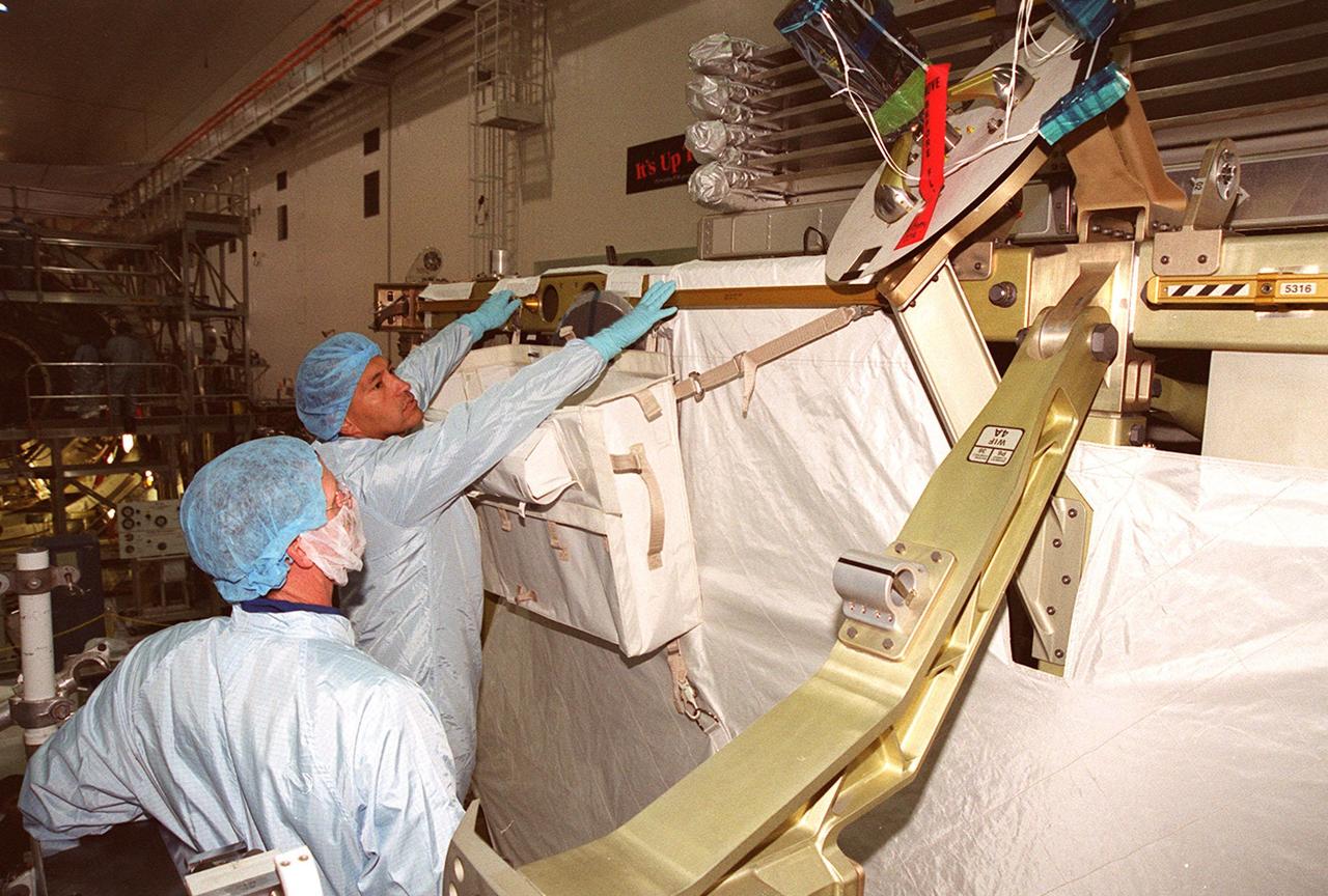 KENNEDY SPACE CENTER, FLA. -- In the Space Station Processing Facility, STS-97 Mission Specialist Carlos Noriega checks out the mission payload, the P6 integrated truss segment, while Mission Specialist Joe Tanner looks on. Mission STS-97 is the sixth construction flight to the International Space Station. The P6 comprises Solar Array Wing-3 and the Integrated Electronic Assembly, to be installed on the International Space Station. The Station’s electrical power system will use eight photovoltaic solar arrays, each 112 feet long by 39 feet wide, to convert sunlight to electricity. The solar arrays are mounted on a “blanket” that can be folded like an accordion for delivery. Once in orbit, astronauts will deploy the blankets to their full size. Gimbals will be used to rotate the arrays so that they will face the Sun to provide maximum power to the Space Station. The mission includes two spacewalks by Noriega and Tanner to complete the solar array connections. STS-97 is scheduled to launch Nov. 30 at about 10:06 p.m. EST