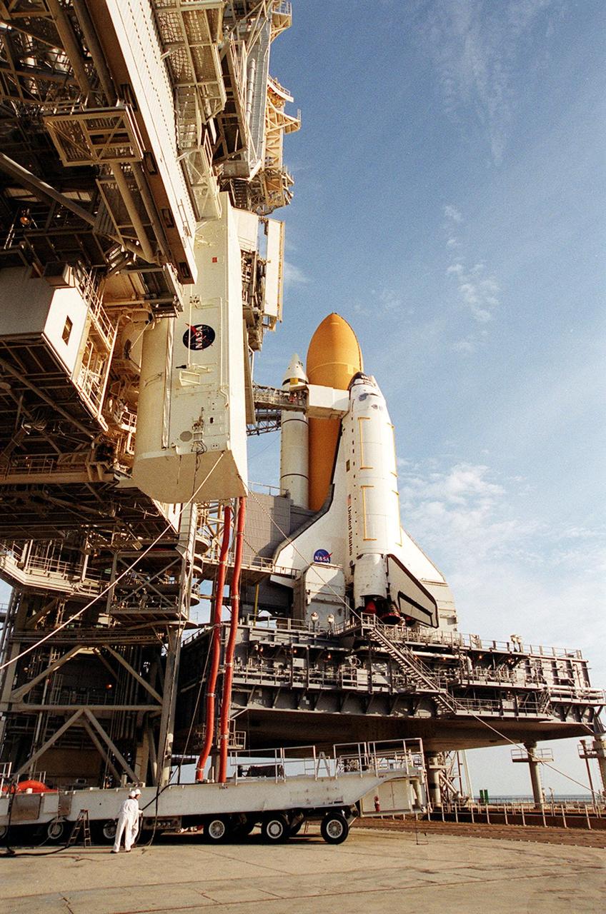 KENNEDY SPACE CENTER, FLA. -- On Launch Pad 39B, the payload transport canister, with the P6 integrated truss segment inside, is lifted higher toward the payload changeout room (PCR) above it. The PCR is the enclosed, environmentally controlled portion of the Rotating Service Structure (RSS) (at left) that supports payload delivery at the pad. At right is Space Shuttle Endeavour with its orange external tank and one solid rocket booster showing behind it. When the RSS is closed around Endeavour, the P6 truss will be moved into the orbiter’s payload bay. The P6, payload on mission STS-97, comprises Solar Array Wing-3 and the Integrated Electronic Assembly, to be installed on the International Space Station. The Station’s electrical power system will use eight photovoltaic solar arrays, each 112 feet long by 39 feet wide, to convert sunlight to electricity. The solar arrays are mounted on a “blanket” that can be folded like an accordion for delivery. Once in orbit, astronauts will deploy the blankets to their full size. Gimbals will be used to rotate the arrays so that they will face the Sun to provide maximum power to the Space Station. Launch of STS-97 is scheduled for Nov. 30 at 10:06 p.m. EST