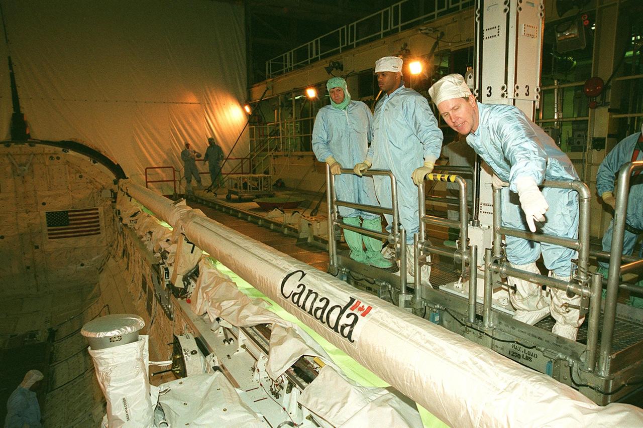 KENNEDY SPACE CENTER, FLA. -- Some of the STS-98 crew look over the Canadian robotic arm in the payload bay of orbiter Atlantis, which is undergoing testing in the Orbiter Processing Facility bay 3. At right, pointing, is Mission Specialist Tom Jones. Second from right is Mission Specialist Robert Curbeam. They and the rest of the crew are at KSC for Crew Equipment Interface Test activities. Launch on mission STS-98 is scheduled for Jan. 18, 2001. It will be transporting the U.S. Lab, Destiny, to the International Space Station with five system racks already installed inside of the module. After delivery of electronics in the lab, electrically powered attitude control for Control Moment Gyroscopes will be activated