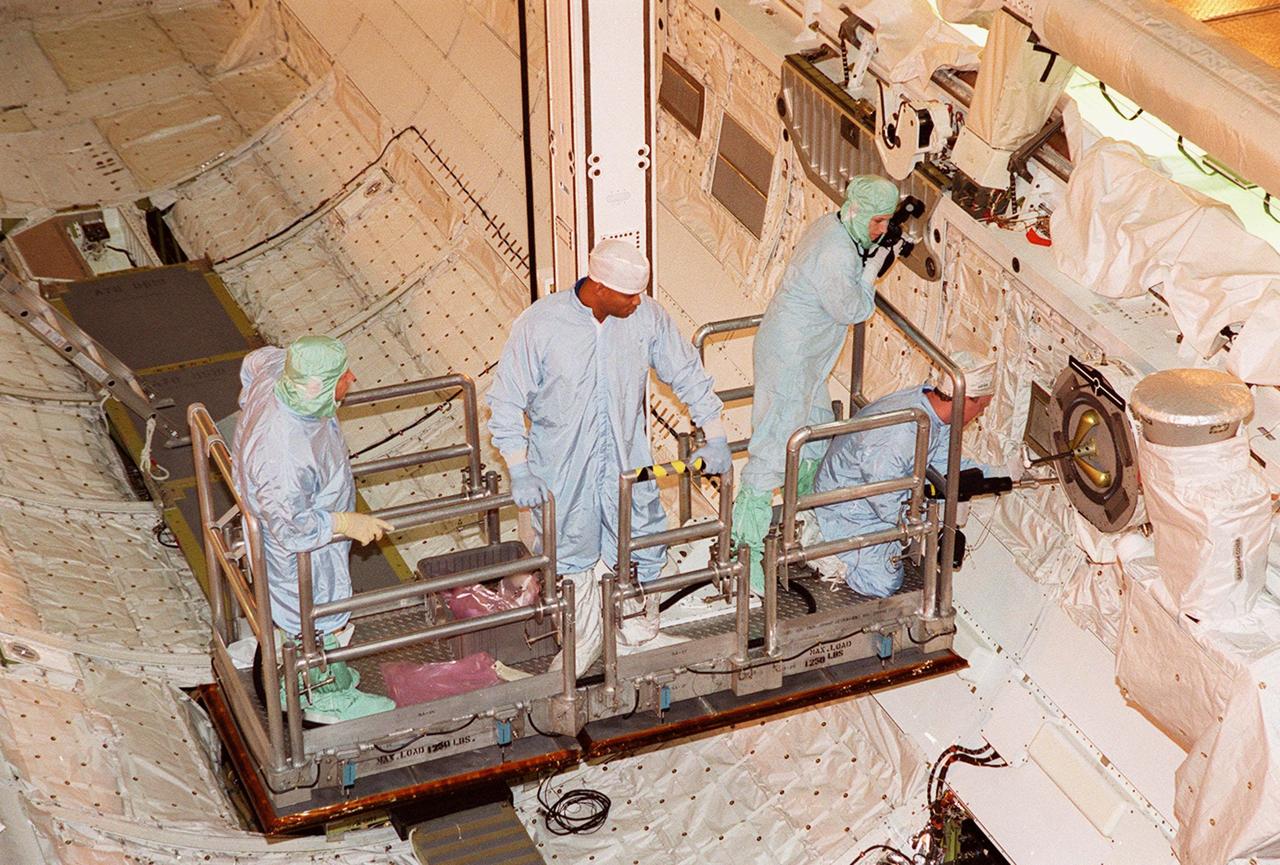 KENNEDY SPACE CENTER, FLA. -- Lowered into the payload bay of the orbiter Atlantis, some of the STS-98 crew look over part of the payload. At center is Mission Specialist Robert Curbeam; at right are Mission Specialists Marsha Ivins (standing) and Tom Jones (kneeling). They and the rest of the crew are at KSC for Crew Equipment Interface Test activities. Launch on mission STS-98 is scheduled for Jan. 18, 2001. It will be transporting the U.S. Lab, Destiny, to the International Space Station with five system racks already installed inside of the module. After delivery of electronics in the lab, electrically powered attitude control for Control Moment Gyroscopes will be activated