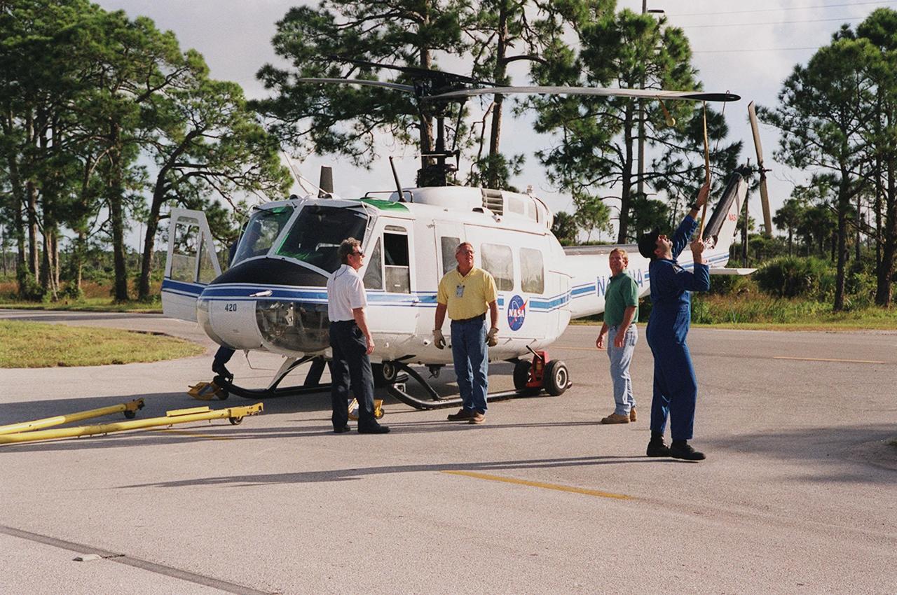 KENNEDY SPACE CENTER, FLA. -- The pilot of the NASA helicopter secures the rotary blade before the helicopter’s transfer to Ransom Road at KSC. It is one of four UH-1H helicopters that will have its blades painted, changing the black to a pattern of white and yellow stripes. The pattern provides better visibility in smoke and fire conditions. When the rotors are turning, the stripes create a yellow and white circle that is more easily seen by a second helicopter from above. The helicopters, primarily used for security and medical evacuation for NASA, will be used to deliver water via buckets during brush fires. The change was made to comply with U.S. Fish and Wildlife and Department of Forestry regulations for helicopter-assisted fire control