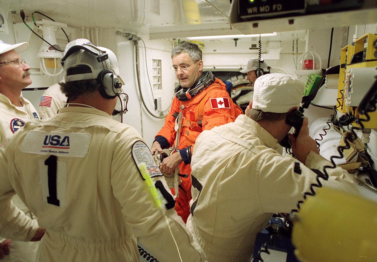 In the White Room, STS-97 Pilot Michael Bloomfield (center) prepares for entry into Space Shuttle Endeavour with the help of the Closeout Crew, (left to right) Al Schmidt, Travis Thompson and Mike Birkenseher. Space Shuttle Endeavour is targeted to launch Nov. 30 at 10:06 p.m. EST for the six construction flight to the International Space Station. Endeavour is transporting the P6 Integrated Truss Structure that comprises Solar Array Wing-3 and the Integrated Electronic Assembly, to provide power to the Space Station. After the 11-day mission, which includes three spacewalks, it is expected to land at KSC Dec. 11 at 6:19 p.m. EST