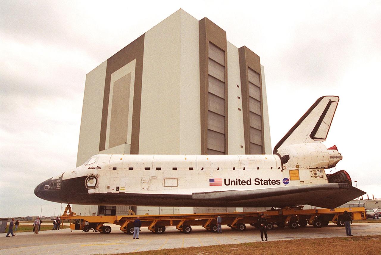 The orbiter Atlantis, on its transporter, heads into the turn toward the Vehicle Assembly Building, in the background. In the VAB it will be raised to vertical and lifted up and into high bay 3 for stacking with its external tank and solid rocket boosters. Atlantis will fly on mission STS-98, the seventh construction flight to the International Space Station. The orbiter will carry in its payload bay the U.S. Laboratory, named Destiny, that will have five system racks already installed inside of the module. After delivery of electronics in the lab, electrically powered attitude control for Control Moment Gyroscopes will be activated. Atlantis is scheduled for launch on Jan. 18, 2001, at 2:44 a.m. EST, with a crew of five