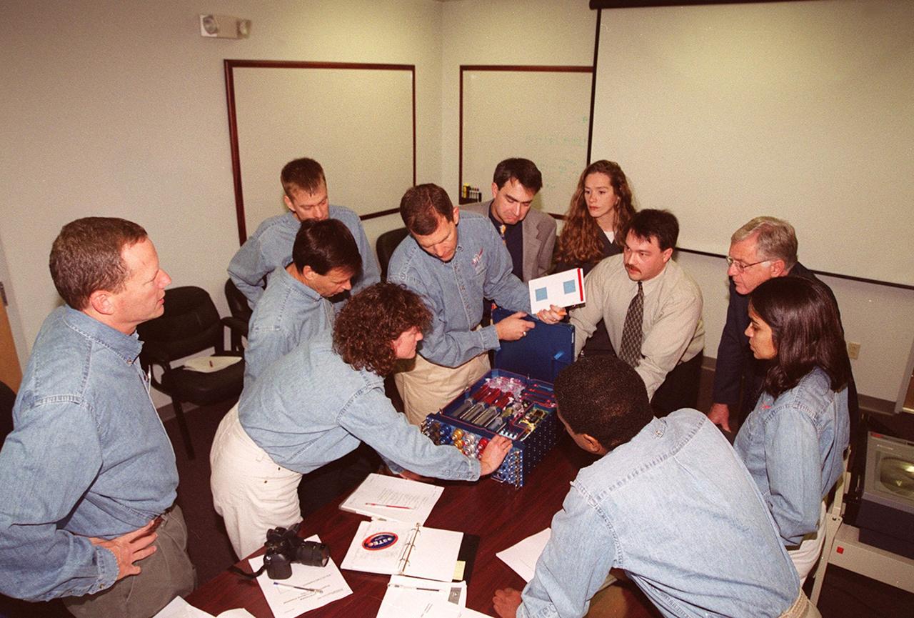 KENNEDY SPACE CENTER, FLA. -- Members of the STS-107 crew take part in In-Flight Maintenance training for their mission. Looking over the OSTEO experiment and paperwork are (at left) Mission Specialists David M. Brown and Laurel Clark and Payload Specialist Ilan Roman of Israel; Pilot William C. “Willie” McCool; and Commander Rick D. Husband. Looking on are project engineers and scientists. On the right are Mission Specialists Michael Anderson (back to camera) and Kalpana Chawla. As a research mission, STS-107will carry the SPACEHAB Double Module in its first research flight into space and a broad collection of experiments ranging from material science to life science. It is scheduled to launch July 19, 2001